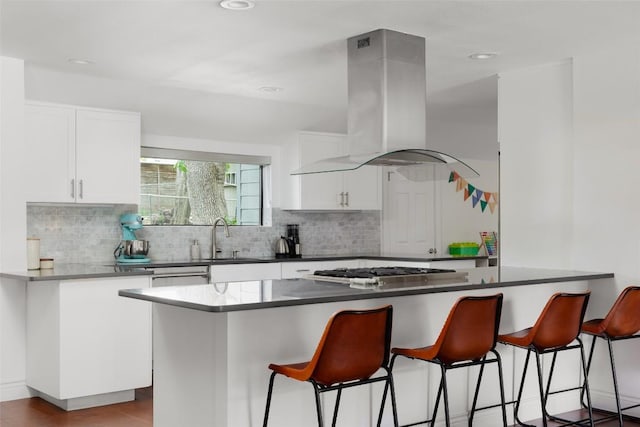 5710 Marilyn Dr, Austin, TX 78757 - kitchen featuring island exhaust hood, a breakfast bar, white cabinetry, tasteful backsplash, and recessed lighting