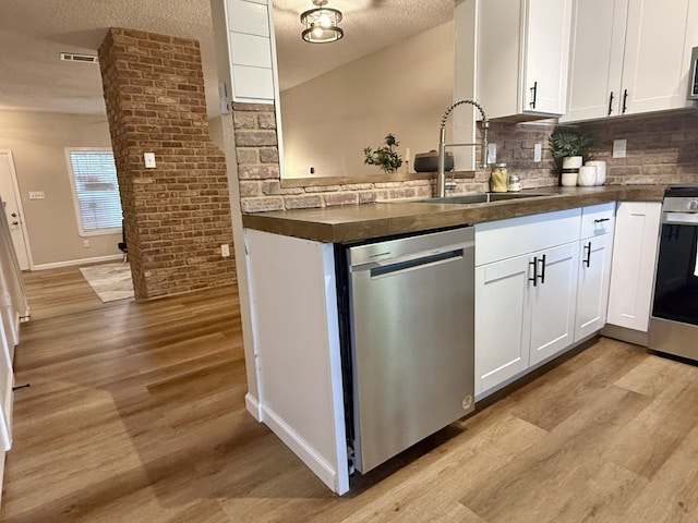 1411 Gracy Farms Ln Unit 130, Austin, TX 78758 - kitchen with appliances with stainless steel finishes, dark countertops, light wood-style flooring, decorative backsplash, and a textured ceiling