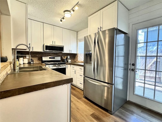 1411 Gracy Farms Ln Unit 130, Austin, TX 78758 - kitchen featuring appliances with stainless steel finishes, dark countertops, decorative backsplash, white cabinetry, and a textured ceiling