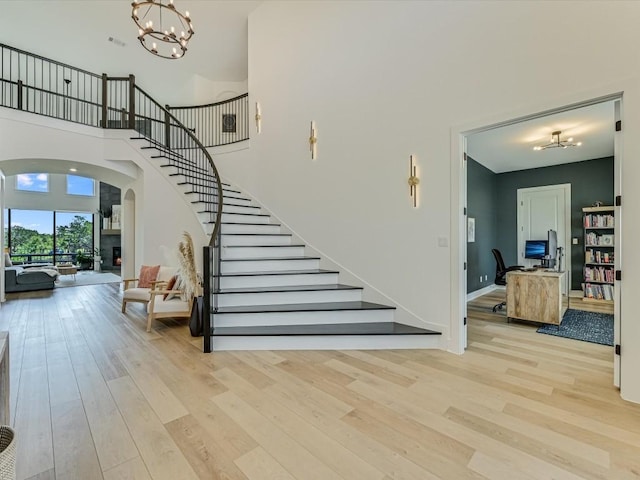 11901 Pier Ct, Austin, TX 78737 - staircase featuring arched walkways, a chandelier, wood finished floors, and a towering ceiling