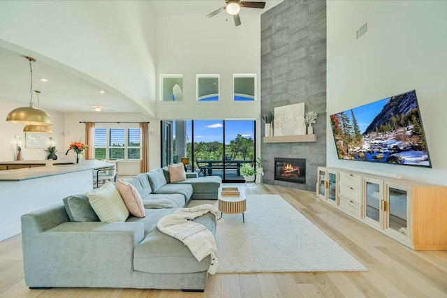 11901 Pier Ct, Austin, TX 78737 - living room featuring a high ceiling, a tile fireplace, light wood-style floors, ceiling fan, and recessed lighting