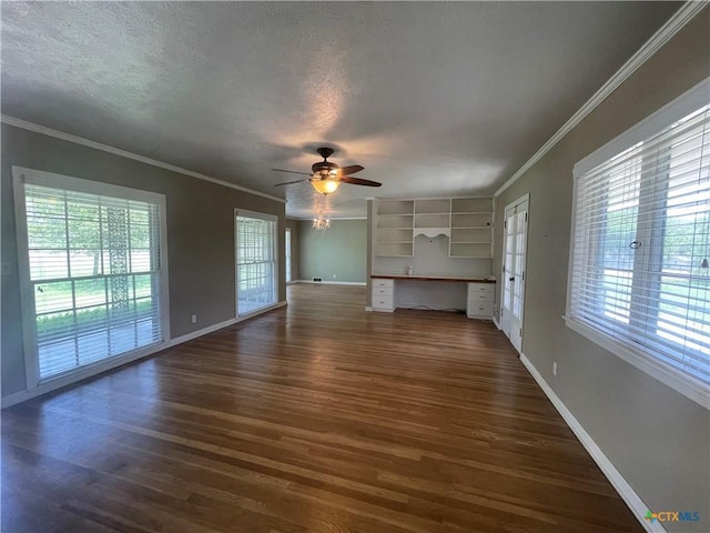 601 S Arnold St S, Lampasas, TX 76550 - unfurnished living room featuring dark wood finished floors, plenty of natural light, built in desk, crown molding, and a textured ceiling