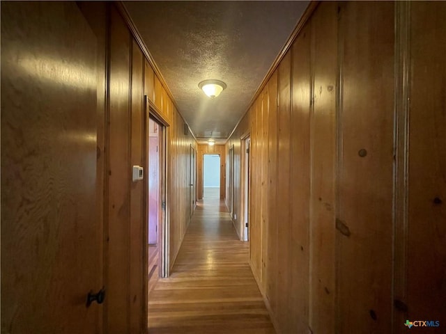601 S Arnold St S, Lampasas, TX 76550 - hallway with a textured ceiling, light wood-style flooring, and wood walls