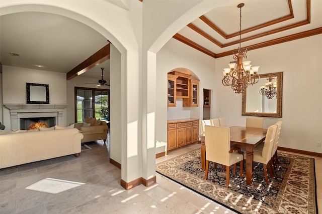 307 Goodnight Dr, Georgetown, TX 78628 - dining area featuring crown molding, a warm lit fireplace, arched walkways, a chandelier, and a raised ceiling