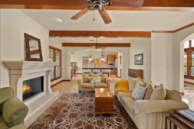307 Goodnight Dr, Georgetown, TX 78628 - living room featuring a ceiling fan, arched walkways, beamed ceiling, a warm lit fireplace, and recessed lighting