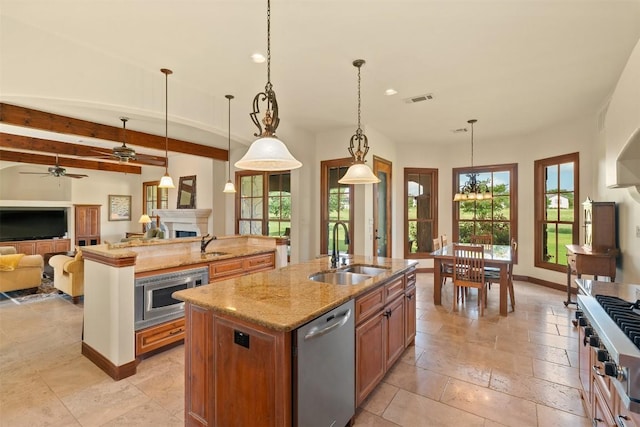307 Goodnight Dr, Georgetown, TX 78628 - kitchen with appliances with stainless steel finishes, a kitchen island with sink, open floor plan, light stone counters, and a fireplace