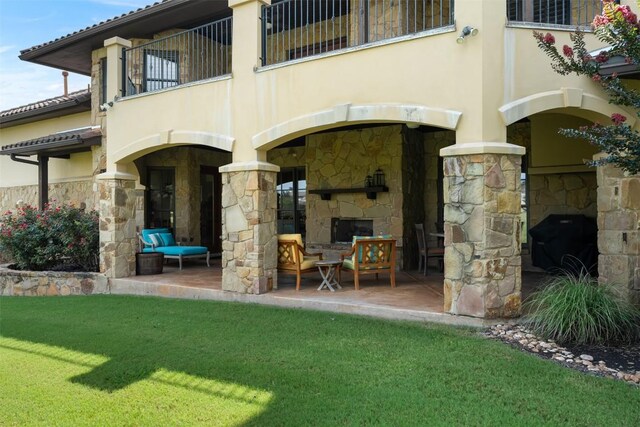 307 Goodnight Dr, Georgetown, TX 78628 - back of house featuring an outdoor stone fireplace, a balcony, stone siding, stucco siding, and a patio