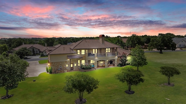 307 Goodnight Dr, Georgetown, TX 78628 - back of property at dusk with a balcony, stucco siding, a tiled roof, a chimney, and stone siding