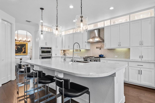203 Black Stone Cv, Driftwood, TX 78619 - kitchen featuring wall chimney range hood, double oven, dark wood-style flooring, backsplash, and recessed lighting