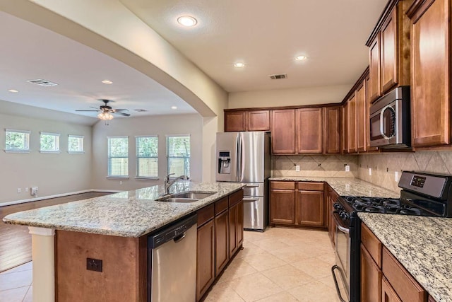 9728 Alex Ln, Austin, TX 78748 - kitchen with stainless steel appliances, ceiling fan, light stone countertops, a center island with sink, and backsplash