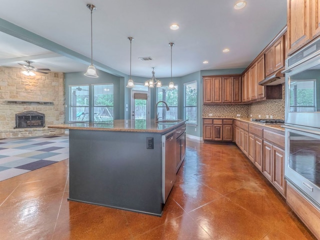 100 N Meadowlark St, Lakeway, TX 78734 - kitchen featuring stainless steel appliances, backsplash, a center island with sink, a ceiling fan, and a fireplace