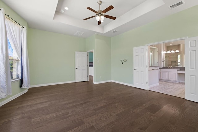 2708 Feathergrass Ct, Cedar Park, TX 78613 - unfurnished bedroom featuring a tray ceiling, multiple windows, wood finished floors, connected bathroom, and recessed lighting