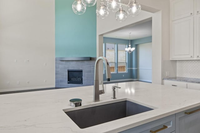 2708 Feathergrass Ct, Cedar Park, TX 78613 - kitchen featuring a chandelier, light stone counters, decorative backsplash, and white cabinets