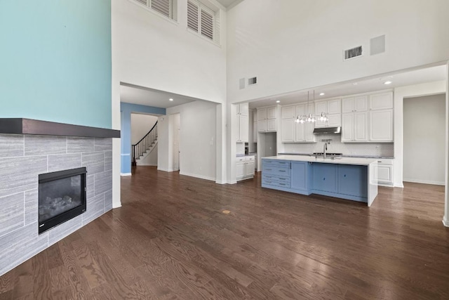 2708 Feathergrass Ct, Cedar Park, TX 78613 - unfurnished living room with a fireplace, stairs, dark wood-style flooring, a high ceiling, and recessed lighting