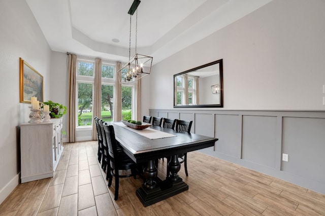 213 Woodland Hills Dr, Georgetown, TX 78633 - dining space with a chandelier, light wood-style floors, wainscoting, a decorative wall, and a raised ceiling