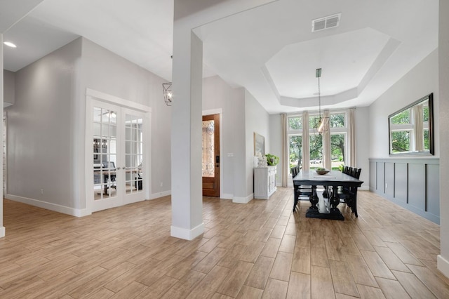 213 Woodland Hills Dr, Georgetown, TX 78633 - dining space featuring light wood-style flooring, french doors, a tray ceiling, and a chandelier