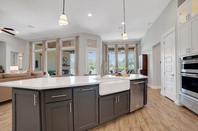 213 Woodland Hills Dr, Georgetown, TX 78633 - kitchen featuring dishwasher, white cabinetry, open floor plan, a center island with sink, and light wood-style floors