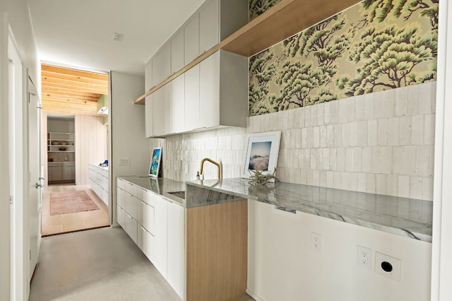 4506 Chiappero Trl, Austin, TX 78731 - kitchen with modern cabinets, concrete flooring, open shelves, stone counters, and backsplash