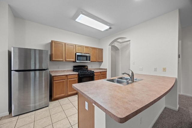716 Bent Wood Pl, Round Rock, TX 78665 - kitchen featuring appliances with stainless steel finishes, arched walkways, a peninsula, and brown cabinetry