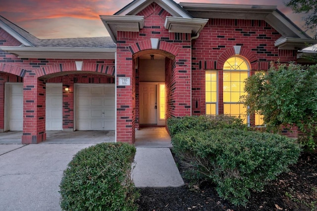 716 Bent Wood Pl, Round Rock, TX 78665 - exterior entry at dusk featuring brick siding, driveway, an attached garage, and roof with shingles