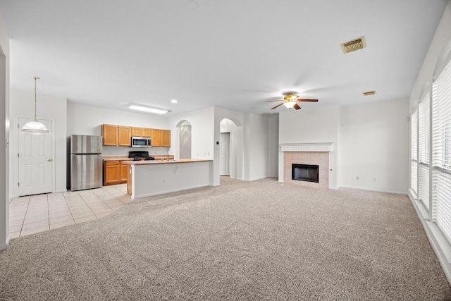 716 Bent Wood Pl, Round Rock, TX 78665 - unfurnished living room with light colored carpet, a ceiling fan, a tile fireplace, light tile patterned floors, and arched walkways