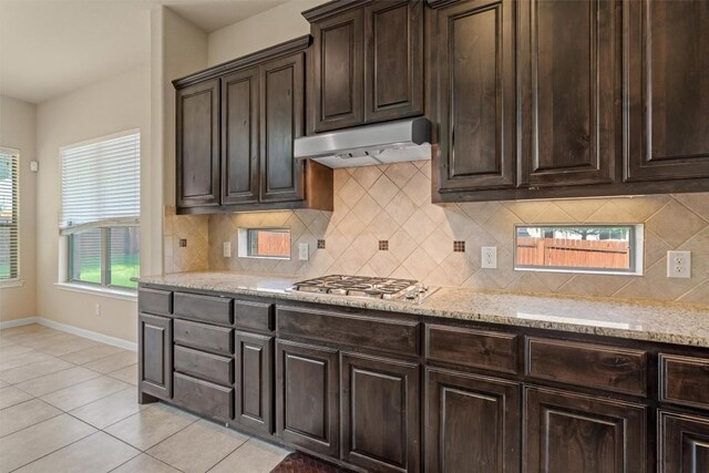 100 Calima Cv, Round Rock, TX 78681 - kitchen with under cabinet range hood, stainless steel gas stovetop, light stone countertops, light tile patterned floors, and backsplash