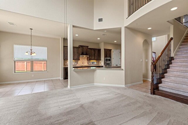 100 Calima Cv, Round Rock, TX 78681 - unfurnished living room featuring light tile patterned floors, light carpet, stairway, a towering ceiling, and recessed lighting
