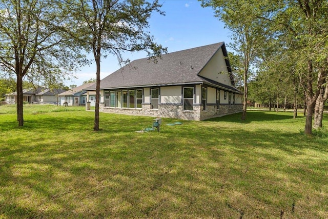 103 W Pauwela Ln, Bastrop, TX 78602 - back of house with stone siding, roof with shingles, and a lawn