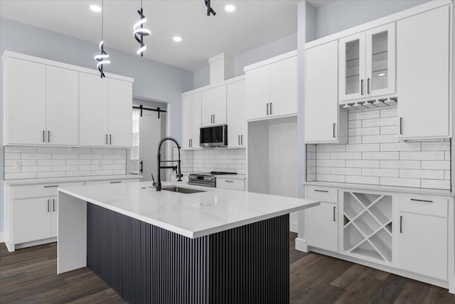 103 W Pauwela Ln, Bastrop, TX 78602 - kitchen with stainless steel appliances, backsplash, white cabinetry, dark wood finished floors, and a barn door