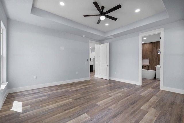 103 W Pauwela Ln, Bastrop, TX 78602 - unfurnished bedroom featuring a tray ceiling, wood finished floors, recessed lighting, ensuite bathroom, and ceiling fan
