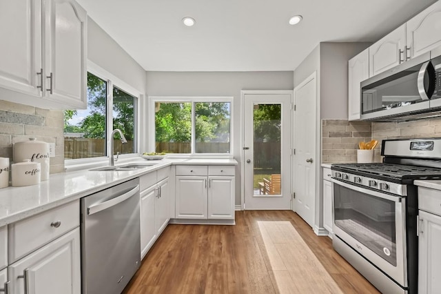 2508 Baxter Dr, Austin, TX 78745 - kitchen with stainless steel appliances, light wood-style floors, tasteful backsplash, white cabinets, and recessed lighting