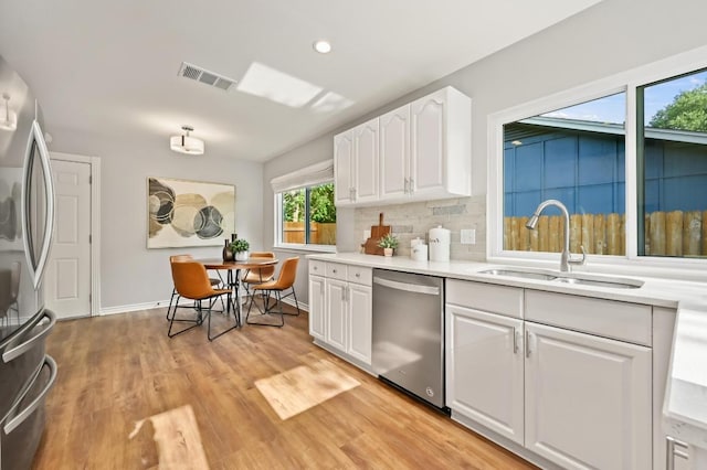 2508 Baxter Dr, Austin, TX 78745 - kitchen with stainless steel appliances, white cabinetry, light countertops, light wood-style floors, and backsplash