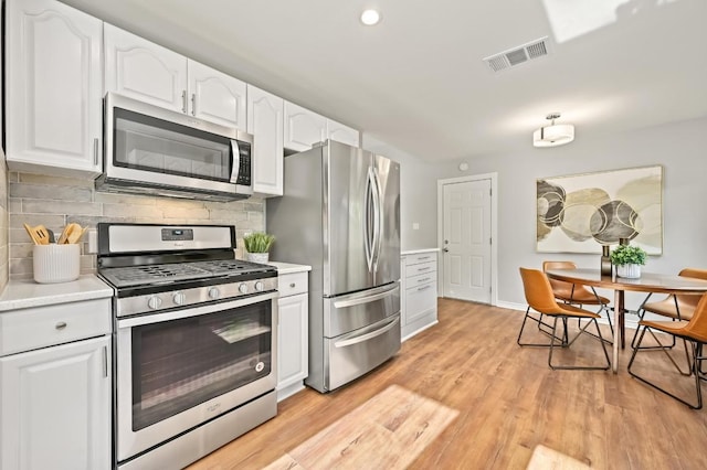 2508 Baxter Dr, Austin, TX 78745 - kitchen with stainless steel appliances, white cabinetry, light countertops, decorative backsplash, and light wood finished floors