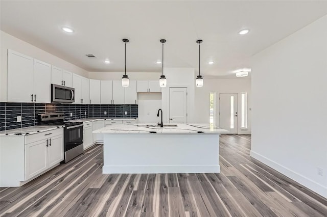 343 Nene Ln, Bastrop, TX 78602 - kitchen with appliances with stainless steel finishes, tasteful backsplash, light wood-style flooring, a kitchen island with sink, and white cabinetry