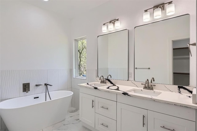 343 Nene Ln, Bastrop, TX 78602 - bathroom with a wainscoted wall, marble look tiles, a freestanding tub, and double vanity