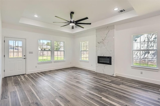 343 Nene Ln, Bastrop, TX 78602 - unfurnished living room with a raised ceiling, plenty of natural light, a ceiling fan, wood finished floors, and recessed lighting