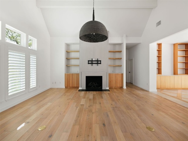 4105 Mcbrine Pl, Austin, TX 78746 - unfurnished living room with high vaulted ceiling, light wood-style floors, built in shelves, and a fireplace with flush hearth