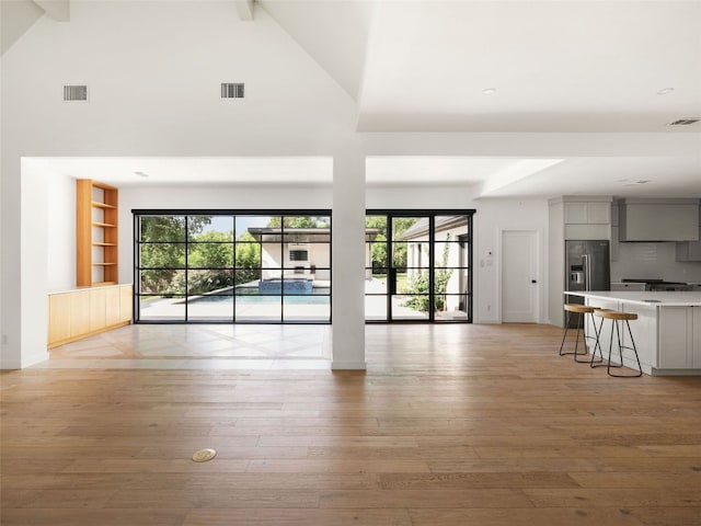 4105 Mcbrine Pl, Austin, TX 78746 - unfurnished living room with high vaulted ceiling, light wood-style floors, plenty of natural light, beamed ceiling, and built in features