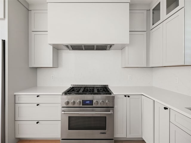 4105 Mcbrine Pl, Austin, TX 78746 - kitchen featuring gas range, custom exhaust hood, backsplash, light countertops, and glass insert cabinets