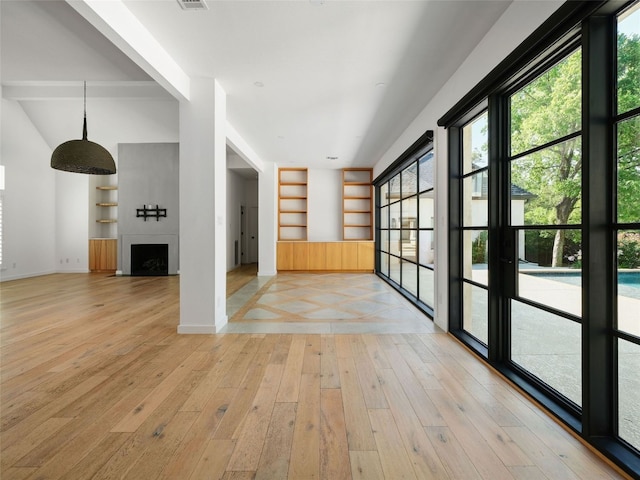 4105 Mcbrine Pl, Austin, TX 78746 - empty room featuring built in shelves, light wood finished floors, and a fireplace