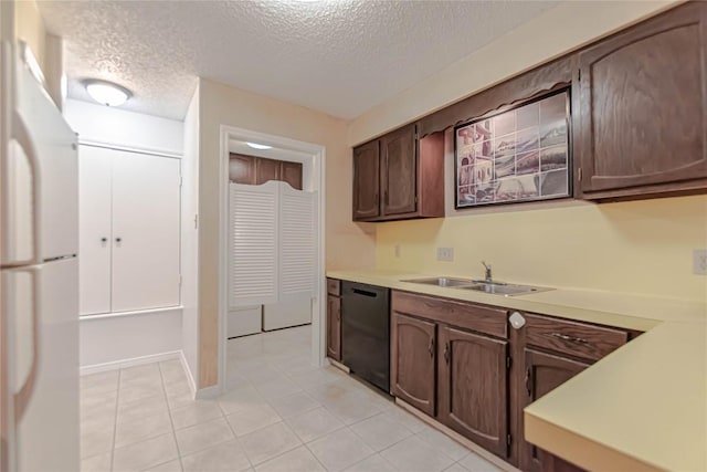 2008 Sandberg Dr, Austin, TX 78752 - kitchen with freestanding refrigerator, black dishwasher, a textured ceiling, light tile patterned floors, and light countertops
