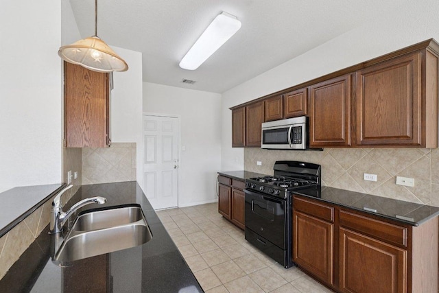 1900 Little Elm Trl Unit 98, Cedar Park, TX 78613 - kitchen with black range with gas stovetop, stainless steel microwave, tasteful backsplash, light tile patterned floors, and decorative light fixtures