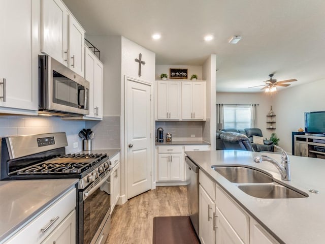 1329 Nokota Bnd, Georgetown, TX 78626 - kitchen with appliances with stainless steel finishes, light wood-type flooring, open floor plan, white cabinetry, and a ceiling fan