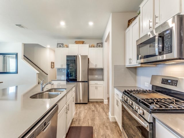 1329 Nokota Bnd, Georgetown, TX 78626 - kitchen with stainless steel appliances, white cabinets, light wood-type flooring, decorative backsplash, and recessed lighting