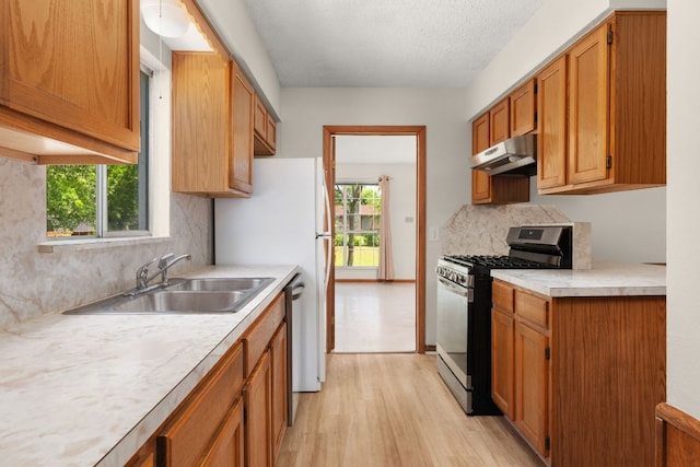 6804 Miranda Dr, Austin, TX 78752 - kitchen featuring stainless steel range with gas cooktop, under cabinet range hood, light wood-style floors, tasteful backsplash, and light countertops
