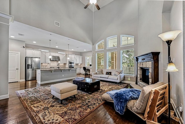 318 Gaspar Bnd, Cedar Park, TX 78613 - living room with dark wood-style floors, ceiling fan, a tiled fireplace, a high ceiling, and recessed lighting