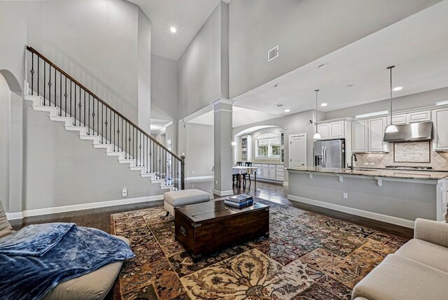 318 Gaspar Bnd, Cedar Park, TX 78613 - living area with decorative columns, dark wood finished floors, a high ceiling, arched walkways, and stairway