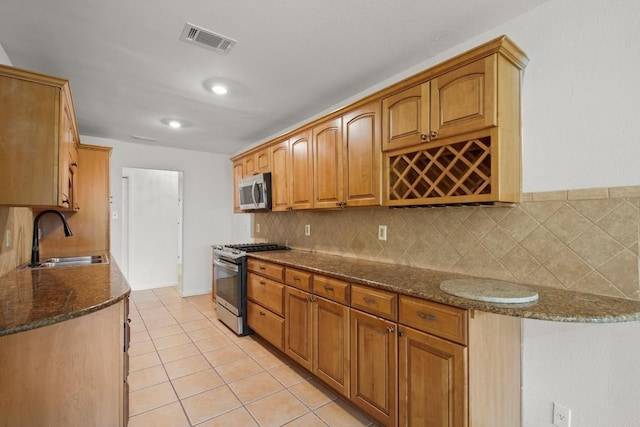 2109 Brandywine Ln, Austin, TX 78727 - kitchen featuring stainless steel appliances, backsplash, dark stone countertops, light tile patterned flooring, and brown cabinets