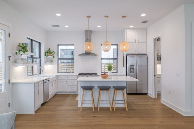 3108 Chennault St, Austin, TX 78723 - kitchen with stainless steel appliances, wall chimney range hood, healthy amount of natural light, white cabinetry, and recessed lighting