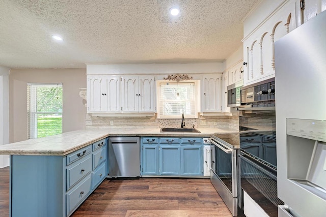 2505 Linwood Rd, Temple, TX 76502 - kitchen featuring stainless steel appliances, blue cabinetry, a peninsula, a textured ceiling, and dark wood finished floors